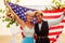 African american female groom in black suit and happy caucasian blonde bride loving together wrapped in america flag on
