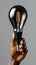 African american female hand holding black lightbulb on grey background, closeup vertical