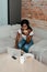 African american freelancer eating toast and using laptop at coffee table with smartphone, plate and cup of tea