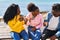 African american friends having breakfast sitting on bench at seaside