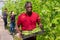 African american gardener stacking boxes with bean in greenhouse