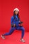 African-American girl in a fitting suit and a Santa`s hat, holds dumbbells and does an exercise of lunges.