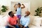 African american girl flexing her biceps while grandfather and father watching at home