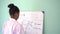 African American girl in lab coat drawing mathematic and science formulas on white board