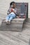 African american girl skater sit on wooden bench in urban space with smartphone chat online outdoors