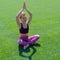 An African American girl in summer in sports clothes raised her hands up and meditates. Young cute black girl sitting on grass in