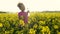 African American girl teenager female young woman drinking from water bottle and running or jogging in field of yellow flowers