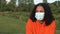 African American girl teenager young woman wearing a face mask during COVID-19 Coronavirus pandemic in an outdoor park