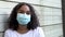 African American girl teenager young woman wearing a face mask during COVID-19 Coronavirus pandemic in an urban city
