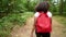 African American girl young woman hiking with a red backpack and holding a cell phone in forest woodland