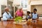 African american grandmother serving breakfast for her two granddaughters in kitchen at home