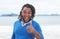 African american guy with dreadlocks at beach showing thumb up