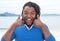 African american guy with dreadlocks listening to music at beach