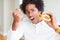 African American hungry man eating hamburger for lunch annoyed and frustrated shouting with anger, crazy and yelling with raised