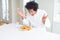 African American hungry man eating hamburger for lunch celebrating crazy and amazed for success with arms raised and open eyes