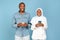 African American Islamic Couple Using Cellphones Texting On Blue Background
