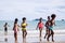 African American, Kids group in swimwear enjoying running to play the waves on beach. Ethnically diverse concept. Having fun after