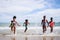 African American, Kids group in swimwear enjoying running to play the waves on beach. Ethnically diverse concept. Having fun after