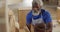 African american male carpenter with digital tablet choosing wooden plank in a carpentry shop