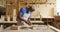 African american male carpenter wearing an apron carving wood with chisel at carpentry shop