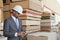 African American male contractor using tablet PC with stacked wooden planks in background