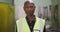 African American male factory worker at a factory wearing a high vis vest