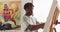 African american male painter painting on canvas in artist studio
