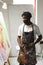 African american male painter wearing face mask painting on canvas in art studio