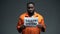 African-american male prisoner holding faulty system sign in cell, human rights
