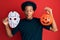 African american man with afro hair wearing hockey mask and halloween pumpking making fish face with mouth and squinting eyes,
