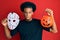 African american man with afro hair wearing hockey mask and halloween pumpking skeptic and nervous, frowning upset because of