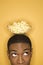 African-American man balancing bowl of popcorn on head.