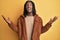 African american man with braids wearing brown retro jacket crazy and mad shouting and yelling with aggressive expression and arms