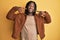 African american man with braids wearing brown retro jacket smiling cheerful showing and pointing with fingers teeth and mouth