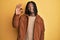 African american man with braids wearing brown retro jacket smiling positive doing ok sign with hand and fingers