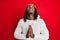 African american man with braids wearing christmas hat begging and praying with hands together with hope expression on face very