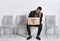 African American man in business suit holding sign LOOKING FOR JOB while waiting for interview in office. Copy space