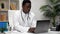 African American man doctor typing text on keyboard laptop in clinic office