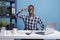 African american man doing military soldier salute while looking at camera in office workspace.