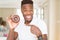 African american man eating chocolate donut very happy pointing with hand and finger