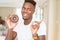 African american man eating chocolate donut very happy pointing with hand and finger to the side