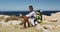 African american man hiking sitting holding a map in coastal countryside