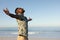 An African American man with his arms outstretched on beach on a sunny day