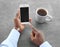 African-American man holding phone with blank screen in hand at table