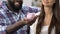 African-american man holding piggy-bank, woman putting coin inside, budget