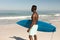 African American man holding surf board on the beach