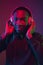 African-american man`s portrait with headphones isolated on gradient studio background in neon light