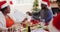 African american man in santa hat pouring drink in glass of senior woman while sitting on dining tab