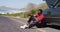 African american man sitting near his broken down car on road