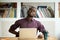 African-american man touching back sitting at desk feeling sudde